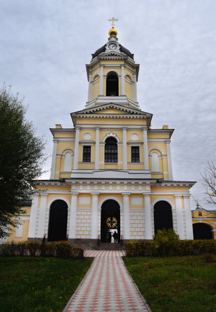 The bell tower above the gate and the path to it in the Orthodox Vysotsky monastery on the background of grey sky in Serpukhov, Russia.の写真素材