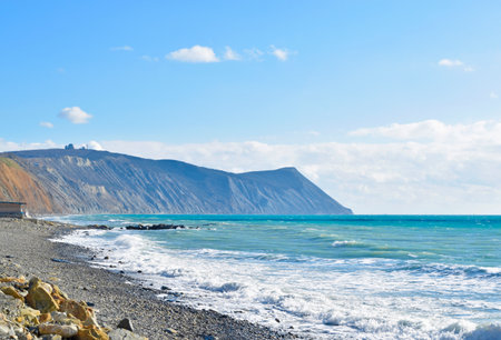 Beautiful spring landscape of turquoise sea and high mountains with a rocky shoreの写真素材