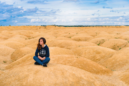 A young woman with long hair walks through the desert with sand dunes of a bizarre shapeの写真素材