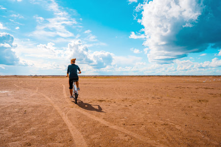 A woman on a Bicycle rides on the sand on a Sunny day, leaving footprints in the sandの写真素材