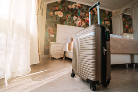 Travel suitcase stands in a white clean hotel room with light from the window, relaxing time, holiday, weekend and traveling concept.の写真素材