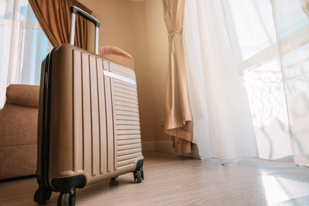 Travel suitcase stands in a white clean hotel room with light from the window, relaxing time, holiday, weekend and traveling concept.の写真素材