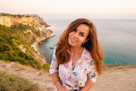 Portrait of a happy woman on the beach high above the sea at sunset with a view of Cape Fiolent in the Crimeaの写真素材