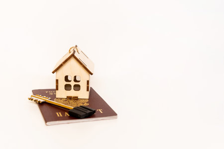 The keys are on the Russian passport and next to a toy house on a white background, the concept of buying real estateの写真素材