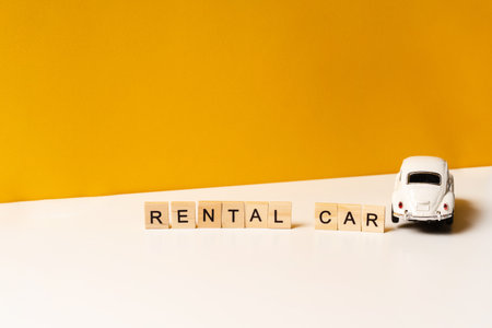 Toy white car on a white table with a yellow background, the inscription of wooden blocks. The...