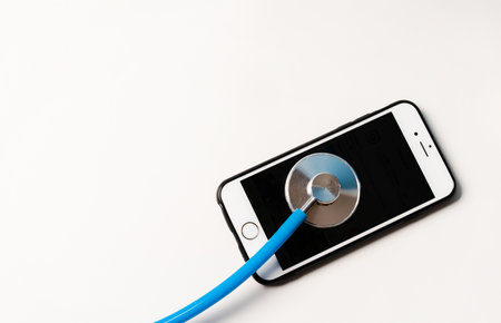 Digital tablet and smartphone being diagnosed with a stethoscope on white background. Repair and Service concept.の写真素材
