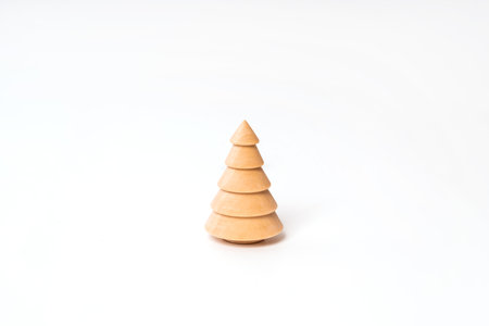 A wooden model of a Christmas tree stands on a white background. Christmas concept, minimalismの写真素材