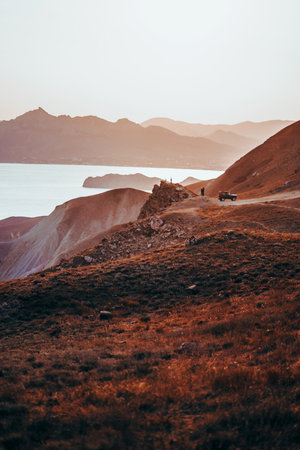 Hilly landscape by the sea in a bright orange sunset. Layers of mountains at sunset, background...