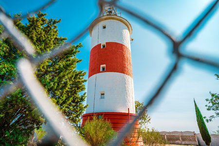 Lighthouse with red stripes on a background of blue sky, beautiful landscapeの写真素材