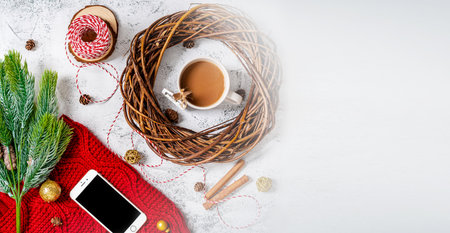 Coffee mug in a soft red winter scarf on a gray background with Christmas decorations. Christmas...