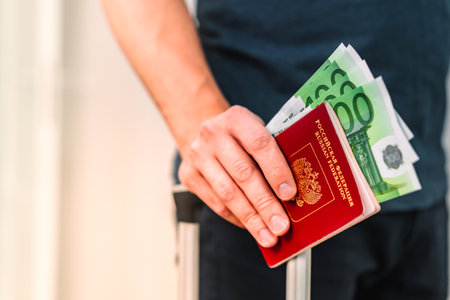 Russian passport and money on hand, holding a suitcase for travelの写真素材