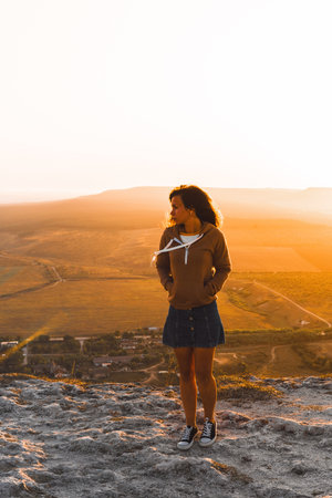 Portrait of a young woman on a mountain in an orange sunsetの写真素材