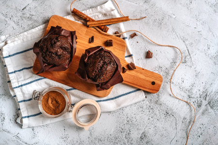 Chocolate cupcakes and cinnamon sticks on a kitchen towel. Food background with copyspace.の写真素材