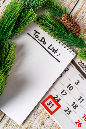 December calendar and notepad with to do list on a wooden background top view. The concept of planning Christmasの写真素材