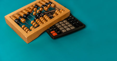 Top view of vintage abacus and modern calculator on a green background, the concept of finance and...