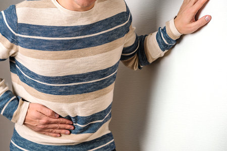 A man feels pain in his stomach clutching a sore spot on a white background with copying space. The...