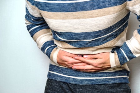 A man feels pain in his stomach clutching a sore spot on a white background with copying space. The concept of poisoning and other gastrointestinal diseasesの写真素材