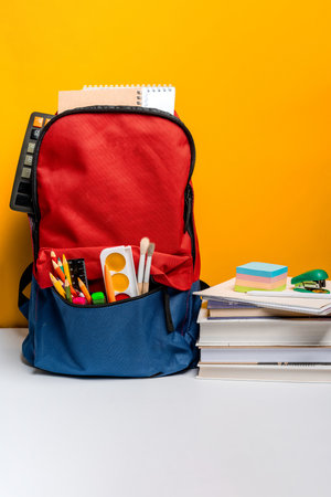 Backpack with different colorful stationery on a yellow background. Banner design