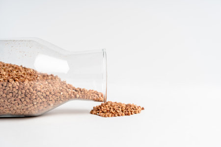 Cereals: buckwheat, rice, oatmeal spilled out of glass containers on a white tableの写真素材