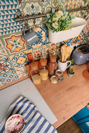 Cozy home style modern kitchen with colorful patchwork tiles, spice jars, glass jars with cereals and other kitchen accessoriesの写真素材