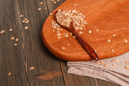 Dry oatmeal is scattered on the wooden table and in a plateの写真素材