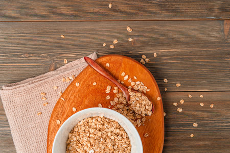 Dry oatmeal is scattered on the wooden table and in a plateの写真素材