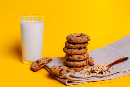 Oatmeal chocolate chip cookies on a kitchen towel on a yellow background with space for textの写真素材