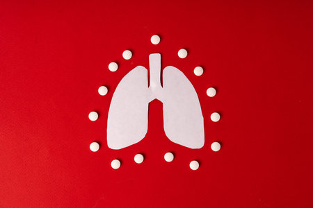 Tablets on paper lungs on a red background. concept of treatment of respiratory diseasesの写真素材