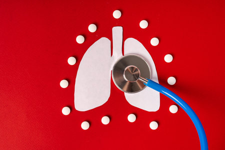 Tablets on paper lungs on a red background. concept of treatment of respiratory diseasesの写真素材