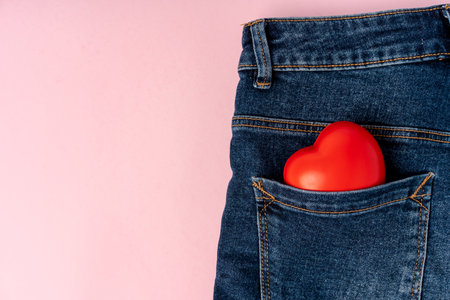 Jeans with a heart on a pink background in the pocket. The concept of Valentine's dayの写真素材