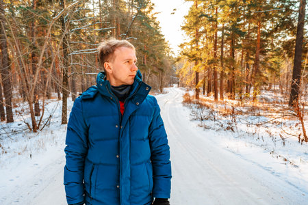 Portrait of a young man on the background of a snowy landscape in a winter pine forest