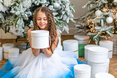 Smiling little girl child in holiday dress holding Christmas giftの写真素材