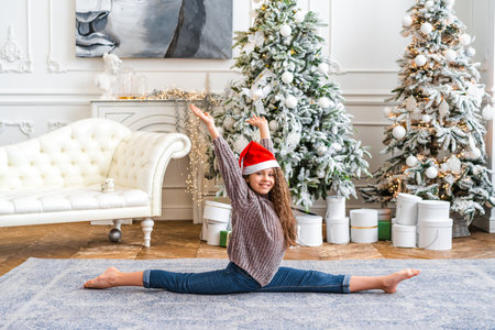 Beautiful little girl performs gymnastic exercises in the studio with Christmas decorationの写真素材