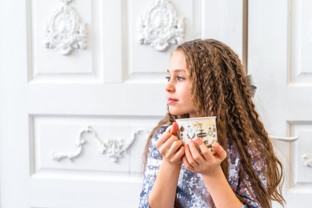 Cute little girl smiles and looks at the camera in a bright studio with Christmas decorationsの写真素材