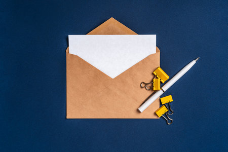 An envelope with a white sheet of paper on a dark blue background and a white pen. Concise, minimalist backgroundの写真素材