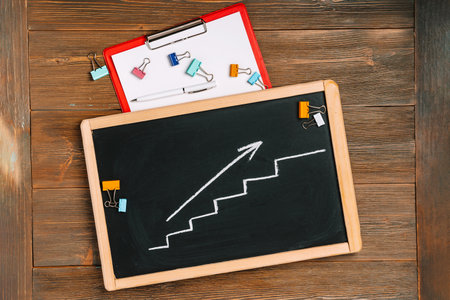 Growth chart with an arrow on a chalkboard, the concept of business solutions and meetingsの写真素材