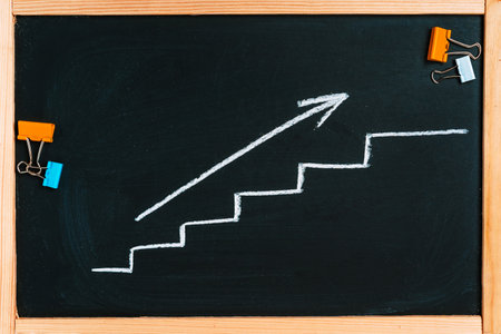 Growth chart with an arrow on a chalkboard, the concept of business solutions and meetingsの写真素材