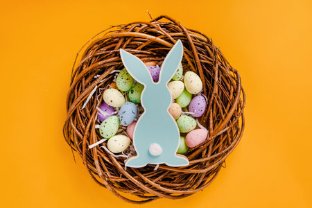 Easter colored eggs lie in a wooden wreath on a yellow background. Beautiful holiday banner and copy...