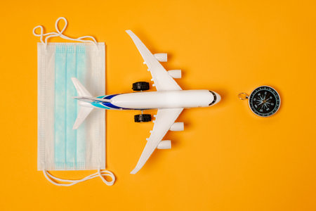 A toy airplane and medical masks on a yellow background. The concept of safe travel