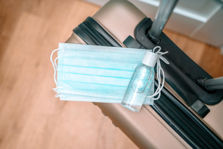 Medical face masks and hand sanitizer are on the travel luggage suitcase. Travel concept during the coronavirus outbreakの写真素材