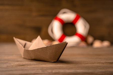 Summer sea banner. Lifebuoy, seashells and a paper boat on a wooden backgroundの写真素材