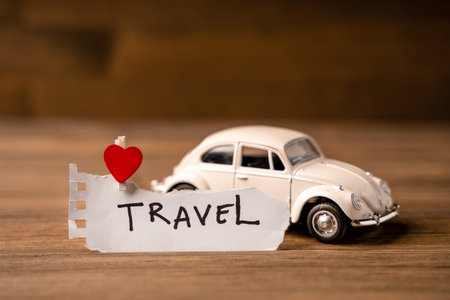 A toy white car with a heart with a piece of paper for notes on a wooden background. Creative place for textの写真素材