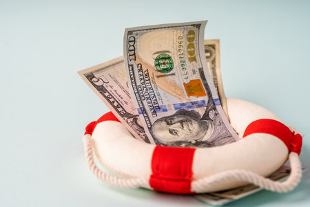 A lifebuoy with banknotes lie on a blue background, the concept of assistance and security in financeの写真素材