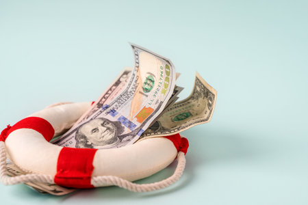 A lifebuoy with banknotes lie on a blue background, the concept of assistance and security in financeの写真素材
