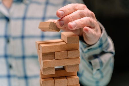 Business man in a shirt builds a tower of wooden blocks as a symbol of development and planning in business, a strategy for successの写真素材