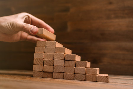 Business concept - hand builds a ladder from wooden blocks. Driving business at the peak concept.の写真素材
