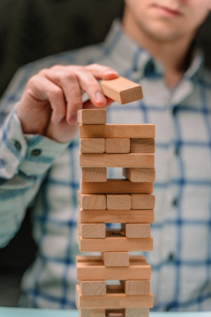 Business man in a shirt builds a tower of wooden blocks as a symbol of development and planning in business, a strategy for successの写真素材