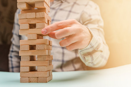 Business man in a shirt builds a tower of wooden blocks as a symbol of development and planning in business, a strategy for successの写真素材