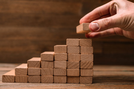 Business concept - hand builds a ladder from wooden blocks. Driving business at the peak concept.の写真素材