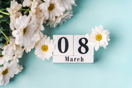 Spring holiday composition on a blue background with daisies and a wooden calendar on March 8, International Women's Dayの写真素材